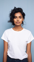 Fototapeta premium Young pretty cool Indian woman model wearing tshirt looking at camera standing on color background. Face skin care cosmetics makeup, fashion ads. Beauty portrait. White t-shirt mock up template .