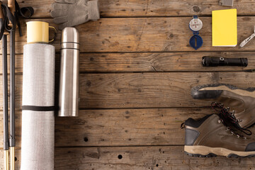 Outdoor hiking gear is neatly arranged on a wooden surface, with copy space