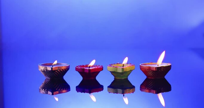 Close up of burning candles in row celebrating diwali on blue background, with copy space