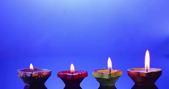 Close up of burning candles in row celebrating diwali on blue background, with copy space