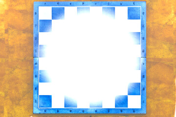 Blue chessboard with white frame on a yellow ocher background, space for text