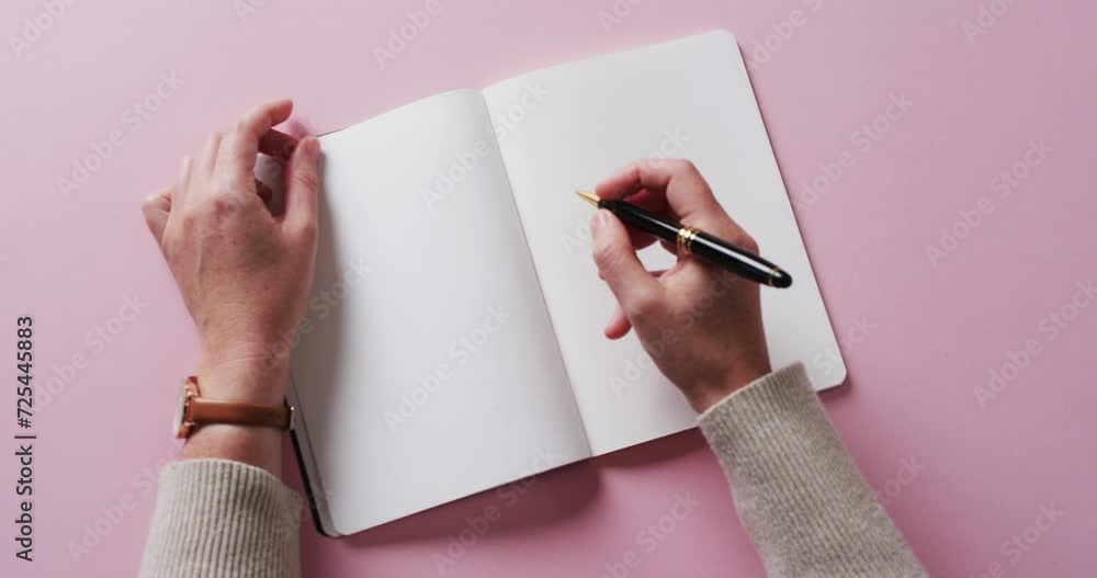 Sticker Close up of hand writing with pen on book with copy space on pink background in slow motion