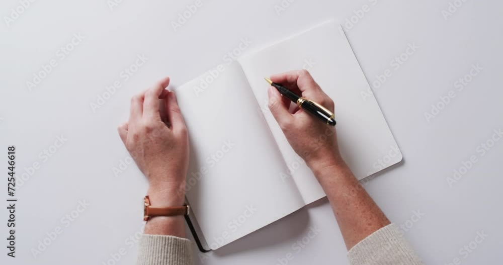 Sticker Close up of hand writing with pen on book with copy space on white background in slow motion