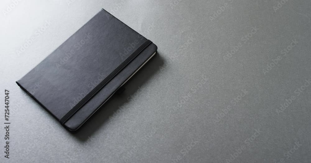 Aufkleber close up of closed gray notebook with copy space on gray background in slow motion