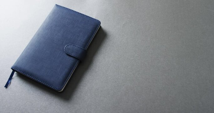 Close up of closed blue notebook with copy space on gray background in slow motion