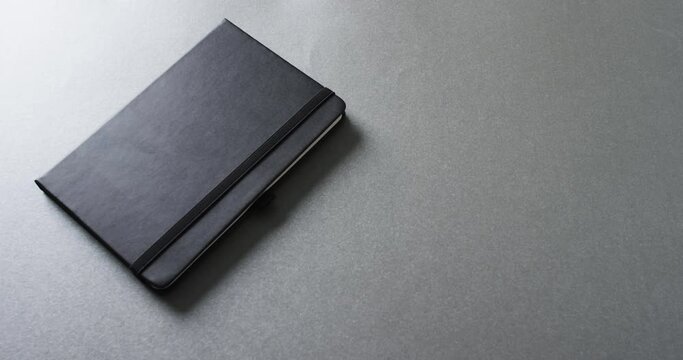 Close up of closed gray notebook with copy space on gray background in slow motion