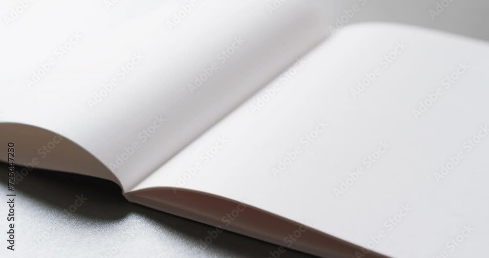 Poster close up of open blank book with copy space on gray background in slow motion