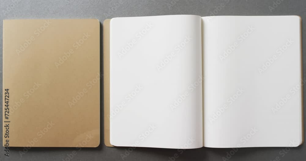 Poster close up of open blank and book brown notebook with copy space on gray background in slow motion