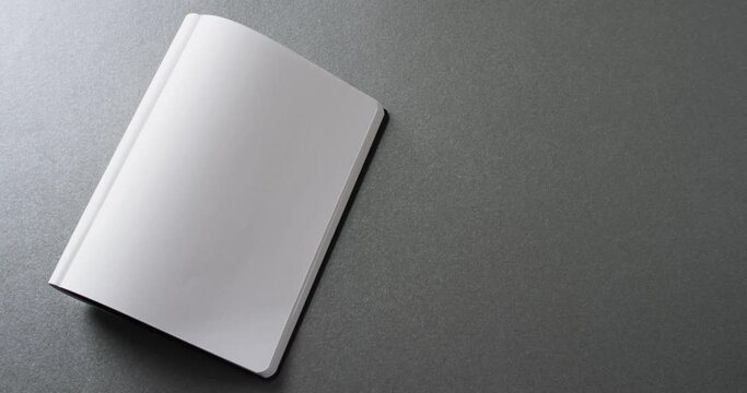 Close up of open blank book with copy space on gray background in slow motion