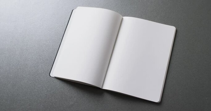 Close up of open blank book with copy space on gray background in slow motion