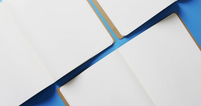 Close up of open blank books with copy space on blue background in slow motion