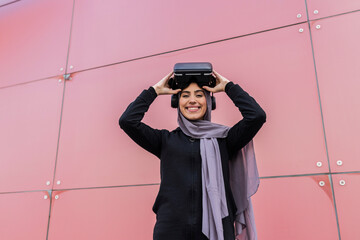 portrait of young woman with virtual reality glasses looking at camera and smilinPortrait of young muslim woman with virtual reality glasses looking at camera and smiling