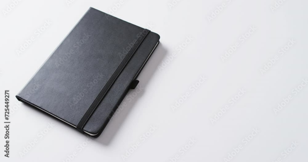 Poster close up of closed black notebook with copy space on white background in slow motion