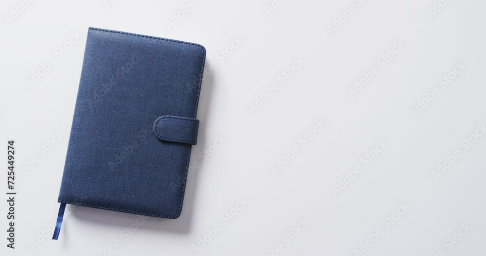Poster close up of closed blue notebook with copy space on white background in slow motion