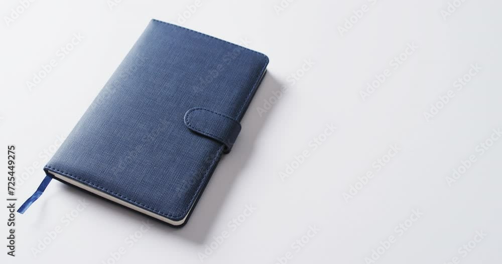 Poster close up of closed blue notebook with copy space on white background in slow motion