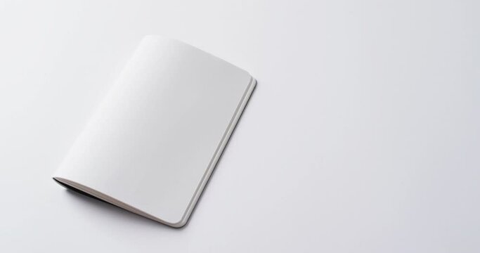 Close up of open blank book with copy space on white background in slow motion