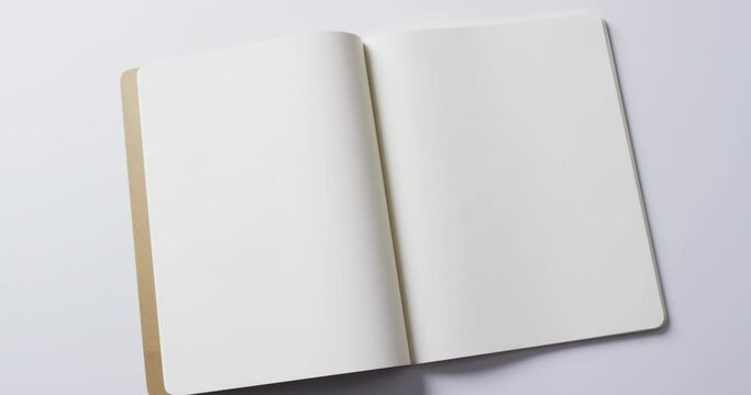 Close up of open blank book with copy space on white background in slow motion