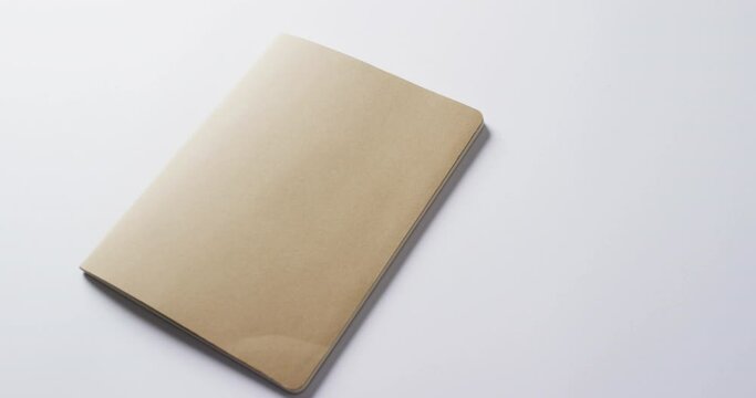 Close up of closed brown book with copy space on white background in slow motion