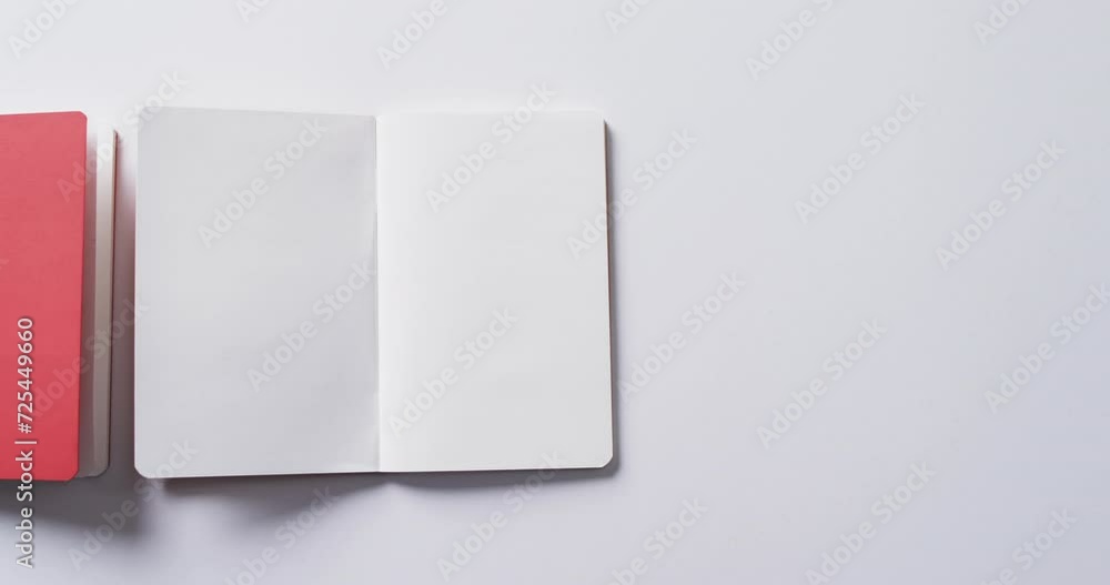 Poster close up of closed red book and open blank book with copy space on white background in slow motion