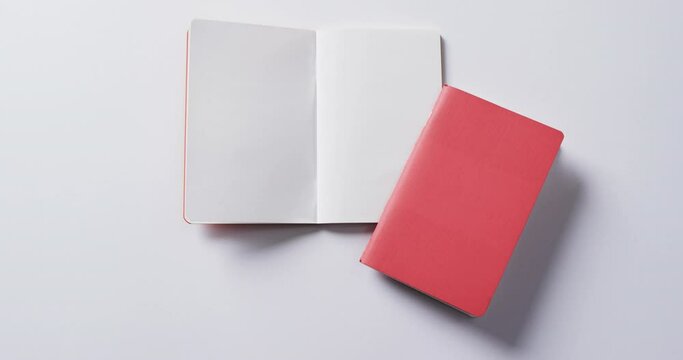 Close up of closed red book and open blank book with copy space on white background in slow motion