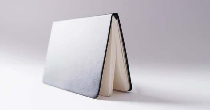 Close up of open black book standing horizontal with copy space on white background in slow motion