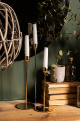 green eucalyptus branches in a vase with books and candles on a wooden table