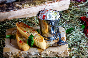 Slices of toast with sour cream and herbs on a wooden board