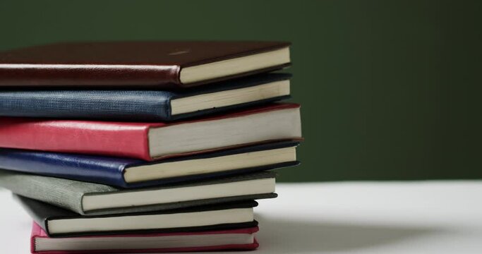 Close up of stack of books on green background, in slow motion