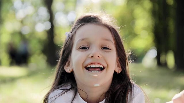 Close-up of a girl's smile. A beautiful little girl 6-7 years old with milk teeth. She is smiling with open mouth in the park