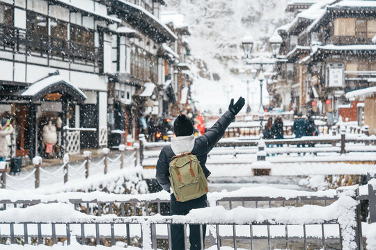 Woman tourist Visiting Ginzan Onsen in Yamagata, happy Traveler sightseeing Japanese Onsen village with Snow in winter season. landmark and popular for attraction in Japan. Travel and Vacation concept