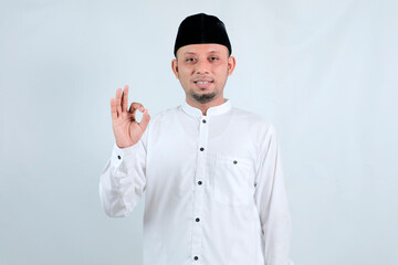 Man wearing a white shirt and black cap making the okay sign.