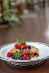 Pancakes with fresh berries and mint on a wooden table