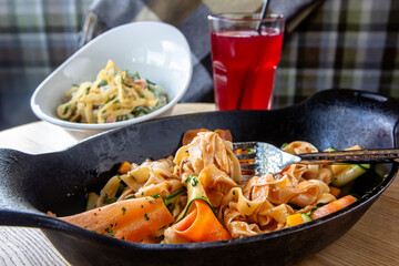 Fettuccine pasta with vegetables in a cast-iron frying pan