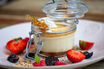 sweet dessert with fresh berries and honey in a glass jar on a wooden table
