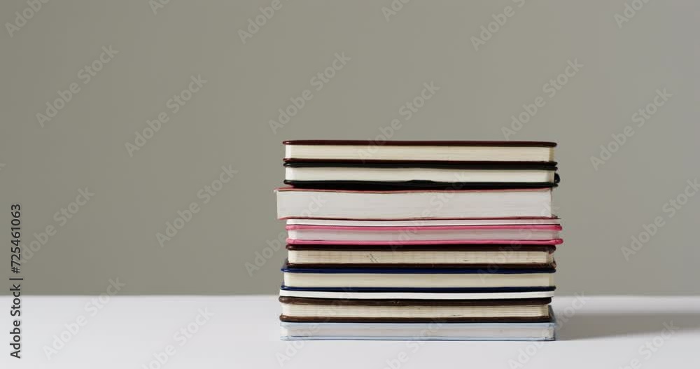 Poster Close up of stack of books on grey background, in slow motion