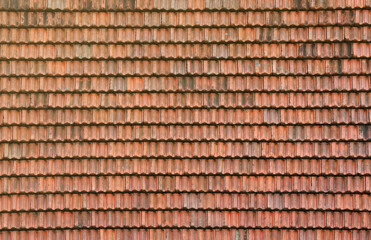 Close up of red terracotta roof shingles with some mildew. Background texture of old roofing material