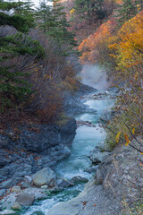 日本　秋田県湯沢市の川原毛地獄の紅葉と蒸気をあげる川