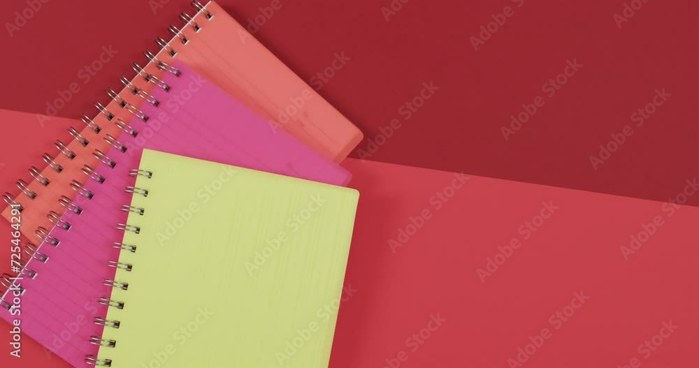 Aufkleber overhead view of colourful notebooks with copy space on red background, in slow motion