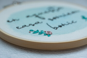 Close-up of an embroidery hoop with a floral decoration and Spanish text