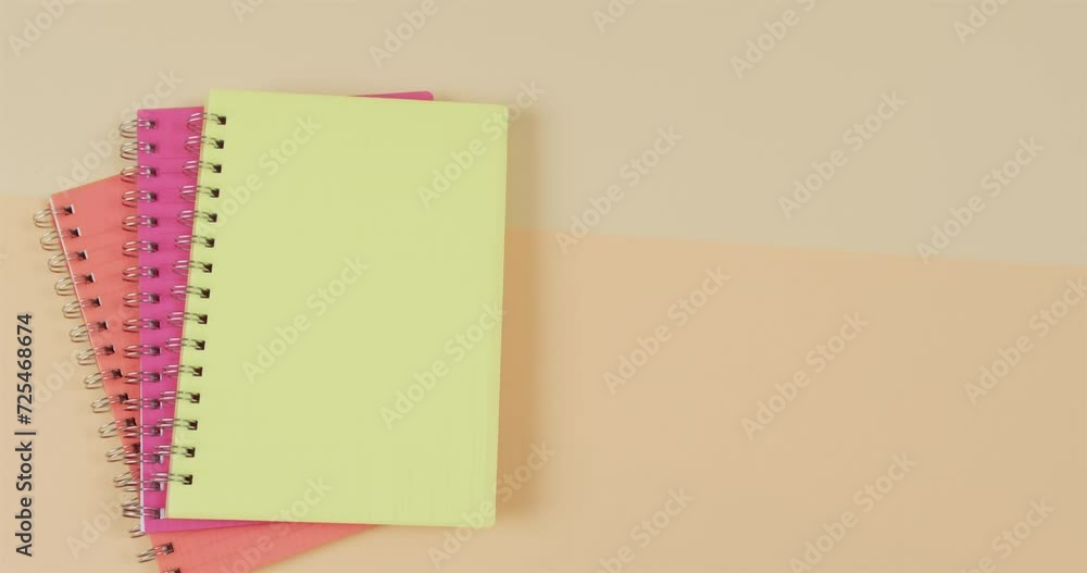 Poster overhead view of colourful notebooks with copy space on beige background, in slow motion