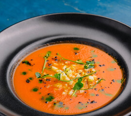 Tomato gazpacho soup on black plate