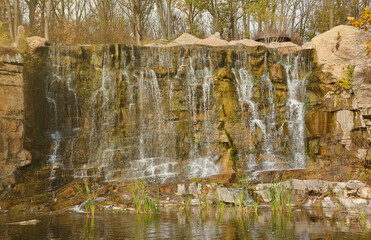 Beautiful waterfall between large rocks in the autumn forest. Sofievskiy park in Uman, Ukraine