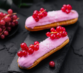 eclair with red currants on black stone