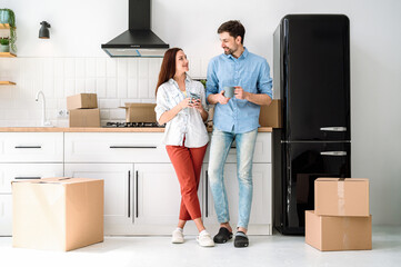 Young family couple moving new apartment, standing on kitchen and drink coffee