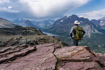 A hiker standing on a high point in the wilderness looking down at a valley with a lake, Two...