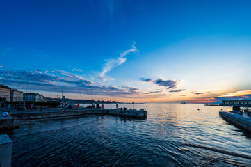 Dusk and night in Trieste. Between historic buildings and the sea. - 725477822