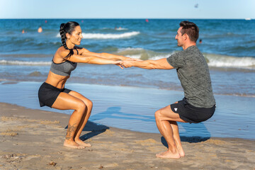 Middle aged couple exercising together on the beach this summer