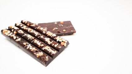 Dark chocolate bars with chopped nuts on a white background, side view. Dessert food. Dark chocolate in Pieces.