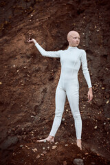Full length portrait of young hairless girl with alopecia in white futuristic suit holding handful...