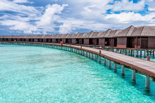 Scenic view of water villas in Maldives with turquoise pristine water and dramatic storm sky 